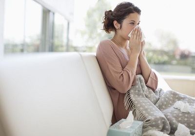 sick woman using tissue to blow her nose - علت خلط پشت گلو